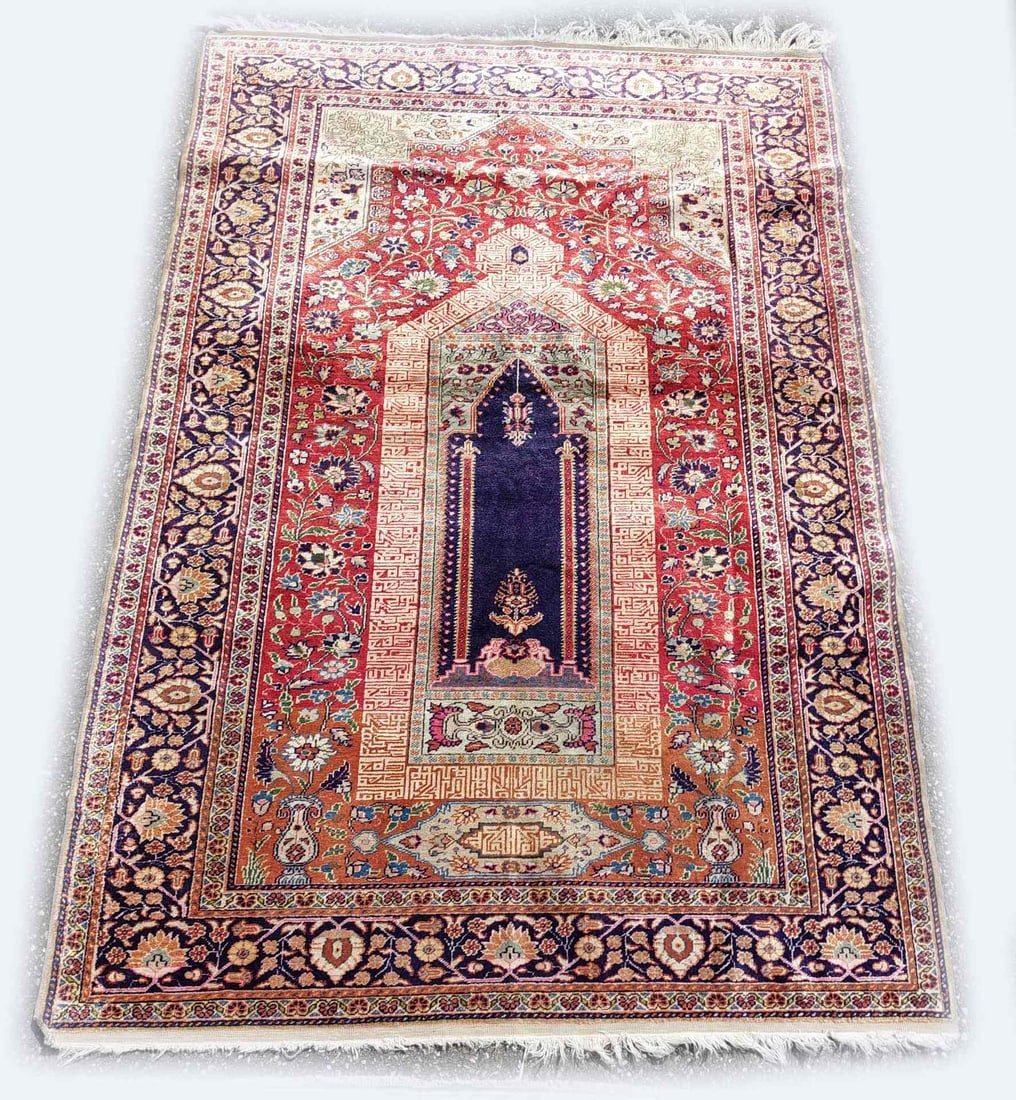 Turkish Kayseri rug, 182 x 121 cm.: Hand-knotted Turkish Kayseri silk rug. Color: red/blue, with floral border. Fringes partially worn. Dimensions: 182 x 121 cm. Otherwise in good condition.