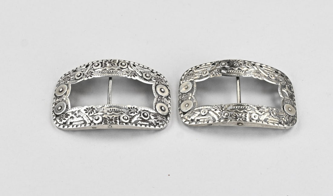 2 Silver shoe buckles: A pair of silver shoe buckles, 833/000, with coins and floral decoration. 1 coin is missing. Maker: van de Ree, Schoonhoven. 9.5 x 6 cm. Approx. 66 grams. In good condition.