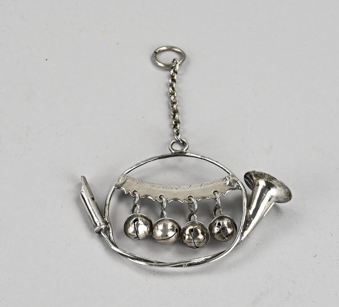 Silver rattle: Silver rattle in the shape of a hunting horn, 833/000, with 4 bells and a whistle. Fitted with a loop with a piece of chain. 10x8cm. Approx. 44 grams. In good condition.
