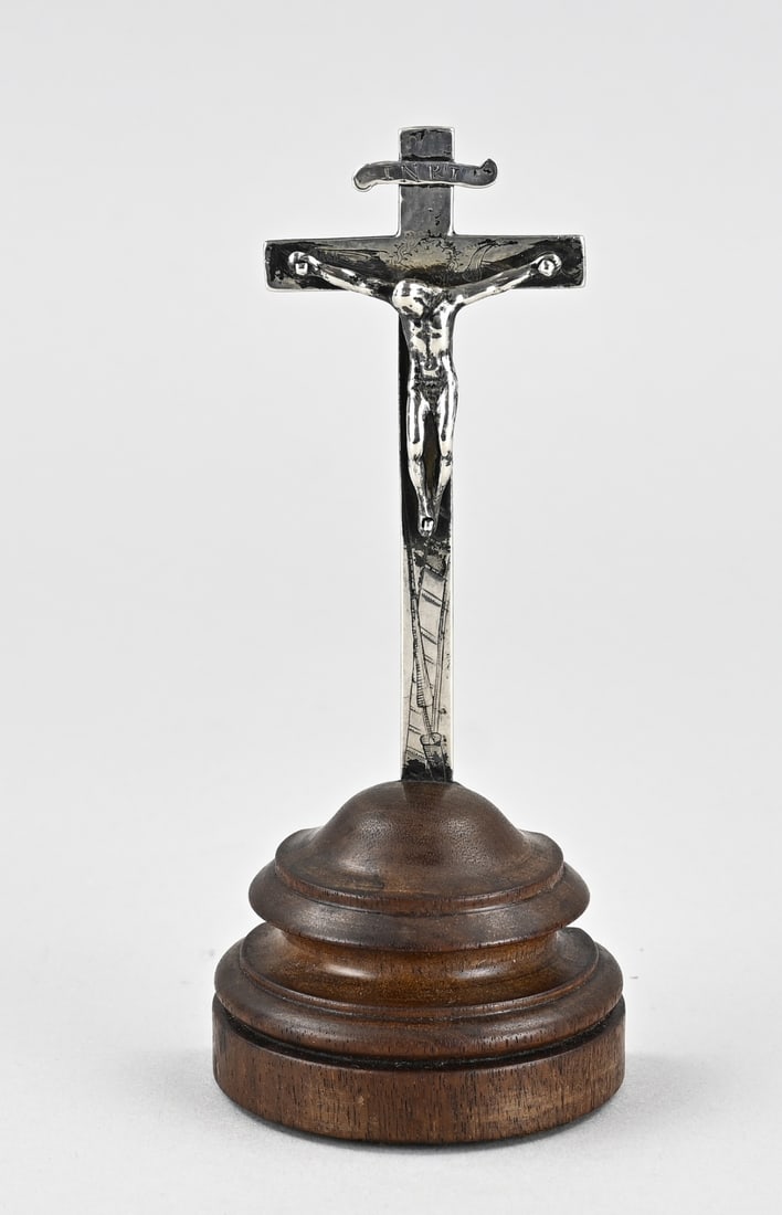 Silver Holy Cross: Silver holy cross mounted on a footed base. >800/000. Cross decorated with engraving and a corpus. Mounted on a wooden base with a flattened back. 6.8 x 15 cm. In good condition. Total with base 102