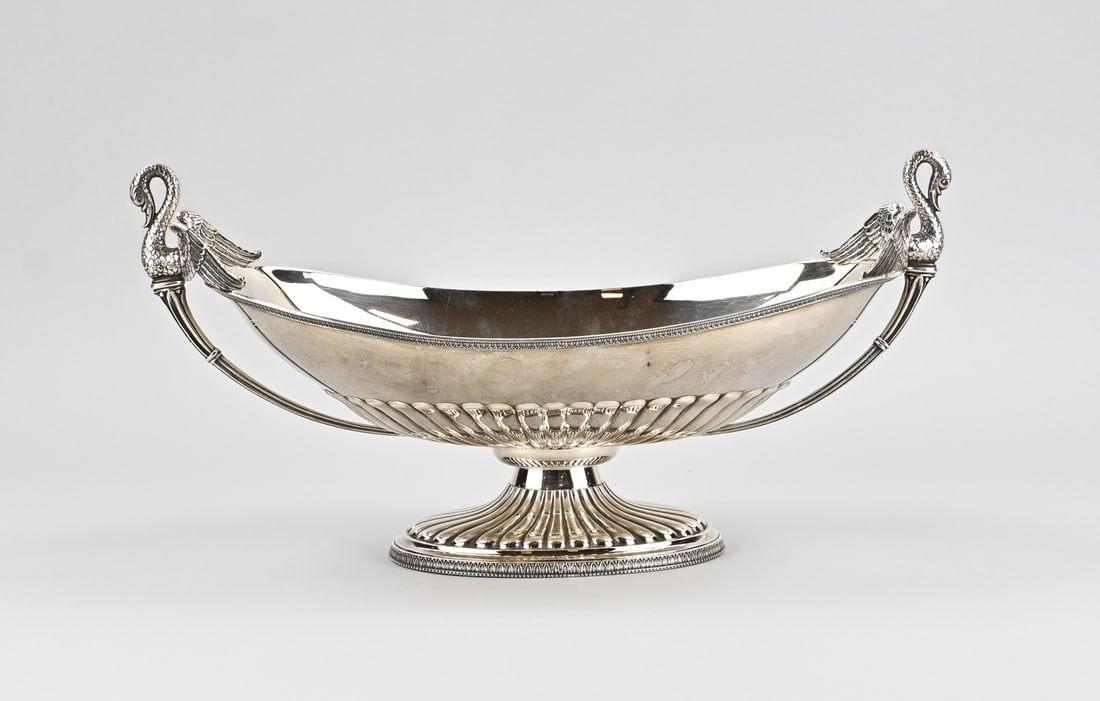 Silver bowl with swans,: Substantial silver bowl, 925/000, oval model with a ridged rim and fluting, set on an oval base. The bowl features handles in the shape of swans with outstretched wings. One handle is broken off.