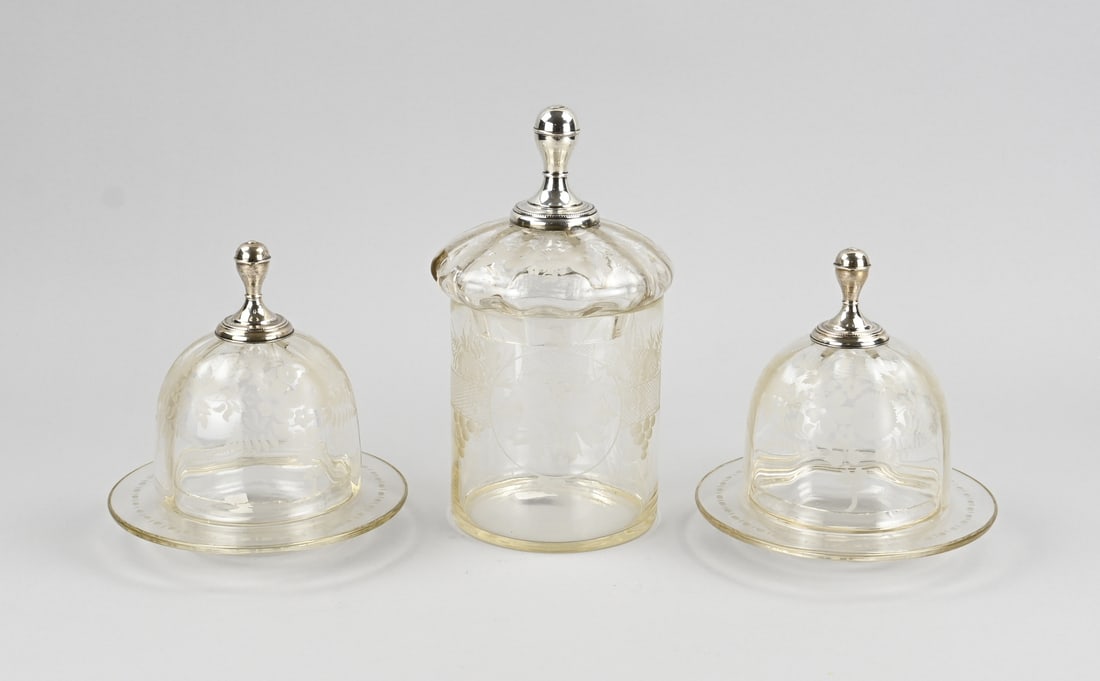 3 Parts etched glass with silver: Three pieces of crystal with etched decoration and silver, 833/000. Two glass domes and a pot richly decorated with floral etched decoration and fitted with a silver knob with pearl decoration. 18-25c