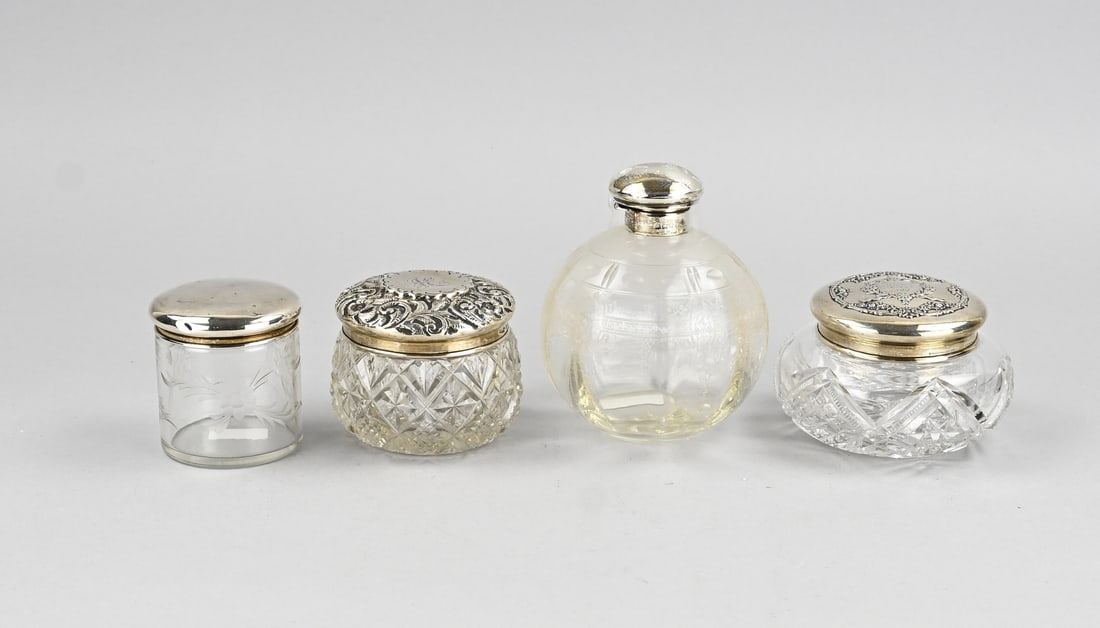4 Bottles with silver: Four crystal flasks with silver, 925/000, 2 oval-cut flasks with lids featuring floral decoration and monogram, a cylindrical flask with a smooth silver lid, and a bulbous flask with etched work and