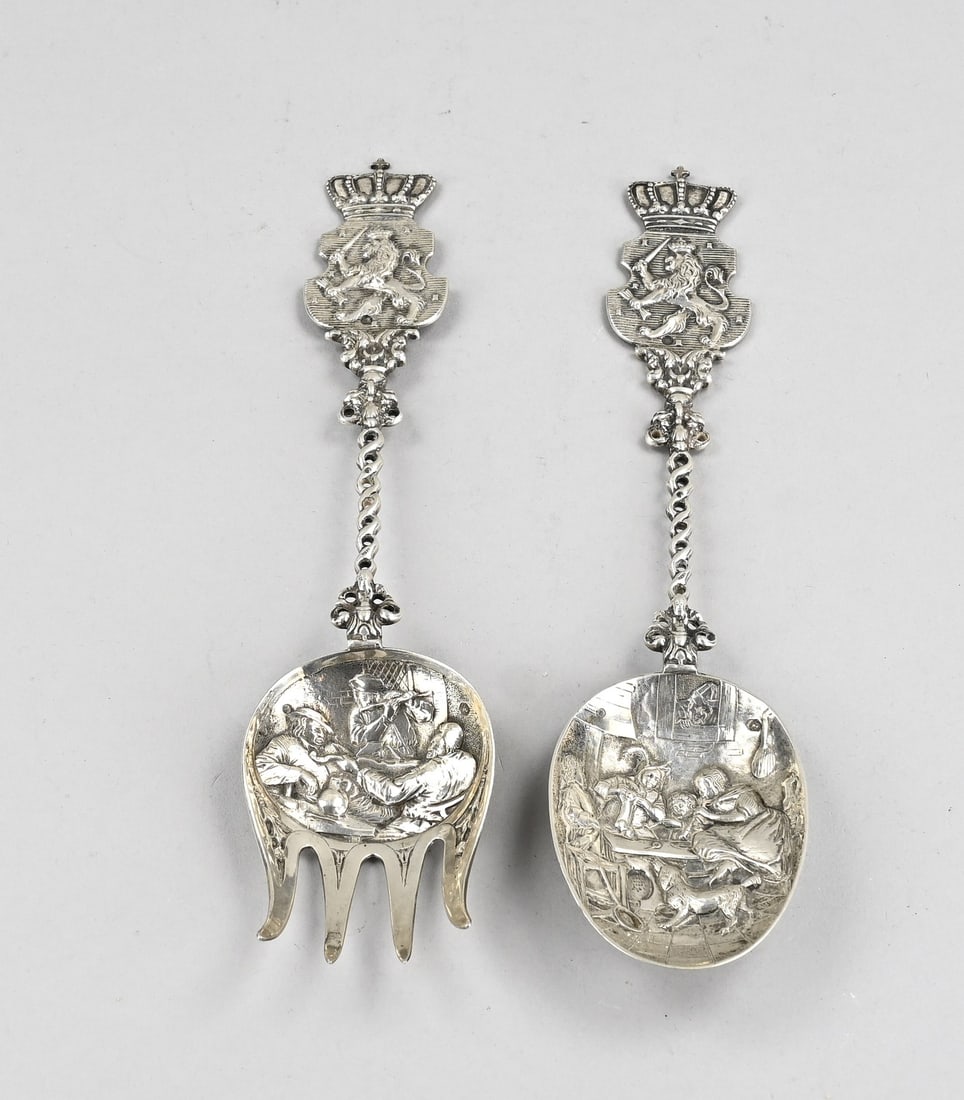 Silver ornamental spoon and fork: Silver ornamental spoon and fork, 833/000, with a bowl decorated with a depiction of figures, a partially twisted handle topped with a crowned coat of arms with a lion. Amsterdam, dated: 1909. 28 cm. 