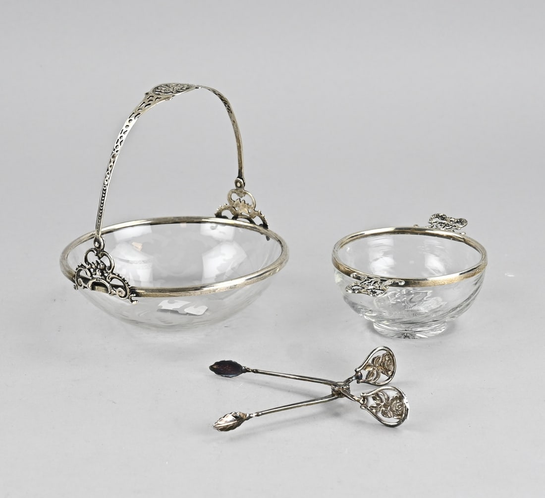 2 Crystal bowls with silver and tongs: Two elegant crystal dishes with silver rims. Etched bonbon dish with silver rim and sawn handle, 800/000. A small crystal dish with silver rim and floral handles, 925/00, .: William Comyns & Sons Ltd,