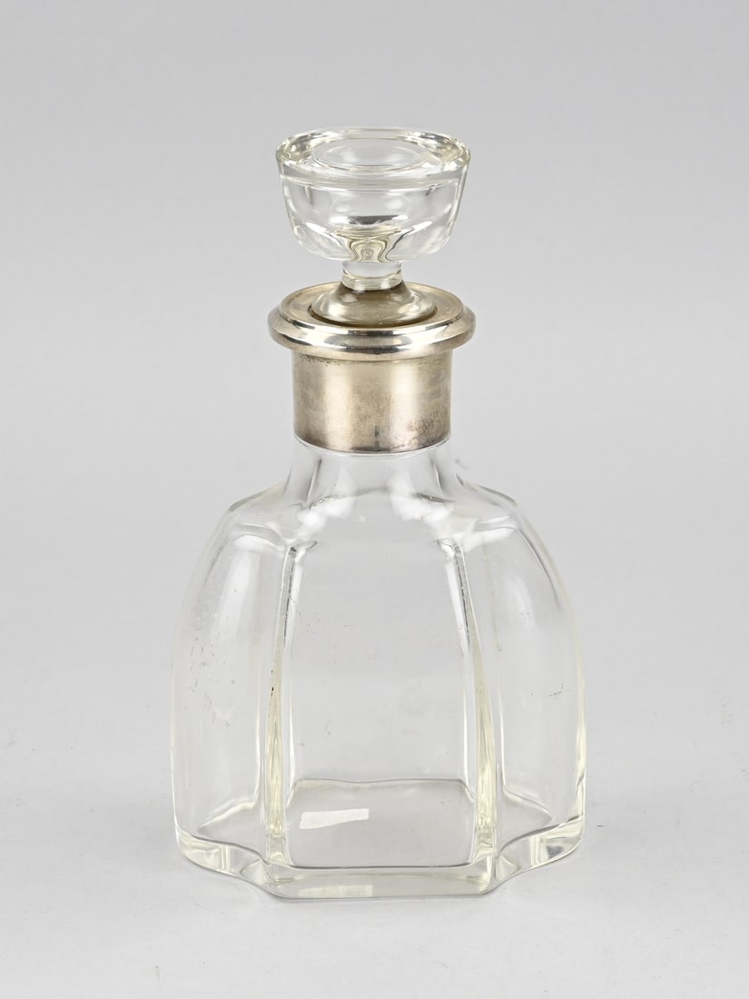 Decanter with silverware: Crystal decanter with wide silver collar, 800/000. Oval-contoured decanter with ribs, a wide smooth rim, and a cylindrical stopper. 13x6x24cm. In good condition.