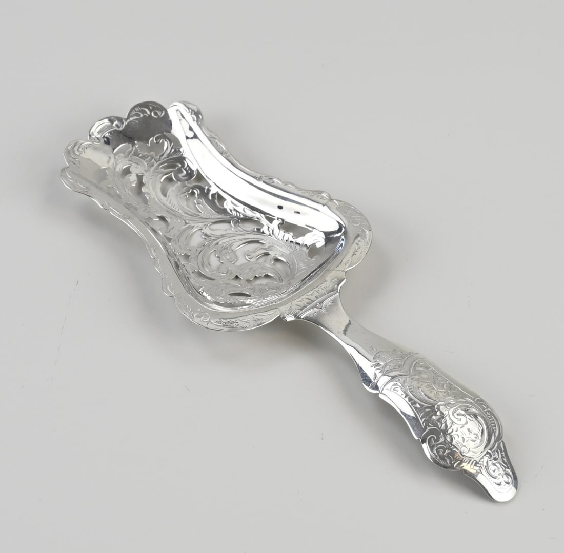 Silver pastry scoop: Silver pastry scoop, 833/000, contoured model with a sawn blade featuring floral decoration. The entire scoop is decorated with floral engraving. MT.: unclear, presumably Amsterdam, 1854. Approx. 39