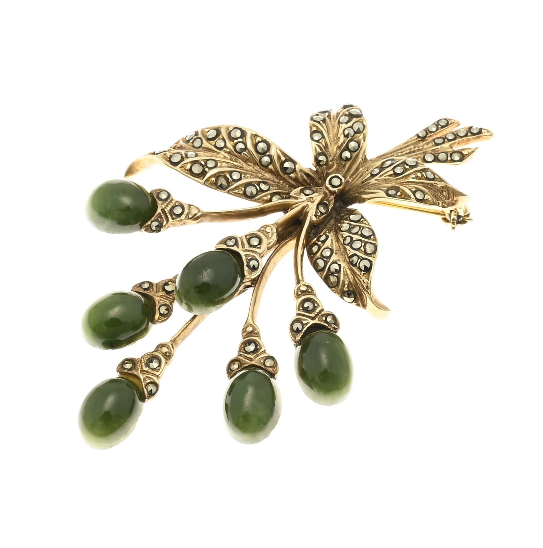 Brooch with nephrite and marquesite: Exceptional brooch, 375/000, decorated as a floral branch with oval cabochon-cut nephrite stones as flowers. The stems and leaves are richly decorated with marcasite stones. 60x39mm. Total approx.