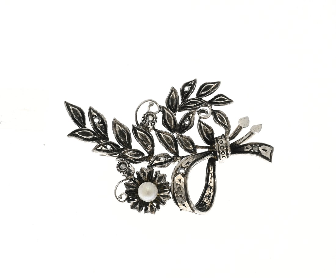 White gold brooch with pearl and diamond: White gold brooch, 750/000, with pearl and diamonds. Branch-shaped brooch with a pearl and a few small diamonds. Approx. 6.9 grams. Pearl damaged. 47x30mm. In reasonably good condition.