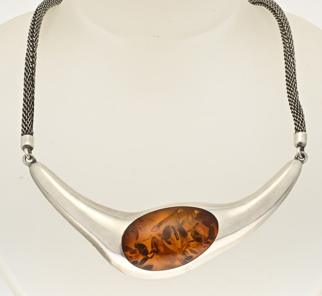 Silver choker with amber: Modern silver choker, 835/000, with a knitted necklace and a large silver element with amber/copal in the center. Width 29 mm. Length 42 cm. Approx. 41.3 grams. In good condition.