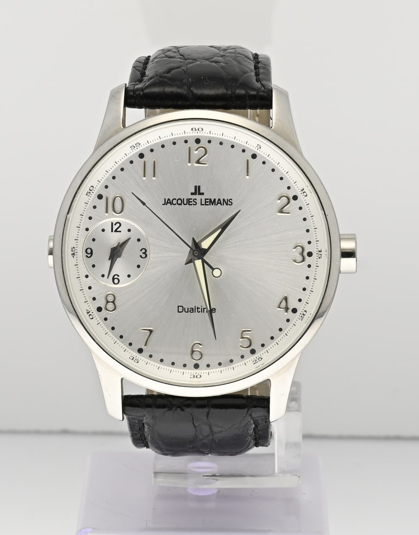 Jacques Lemans, dual time: Jacques Lemans, Dualtime, with a round steel case. Quartz. Mounted on a black leather strap, ø 42 mm. Working. As new.