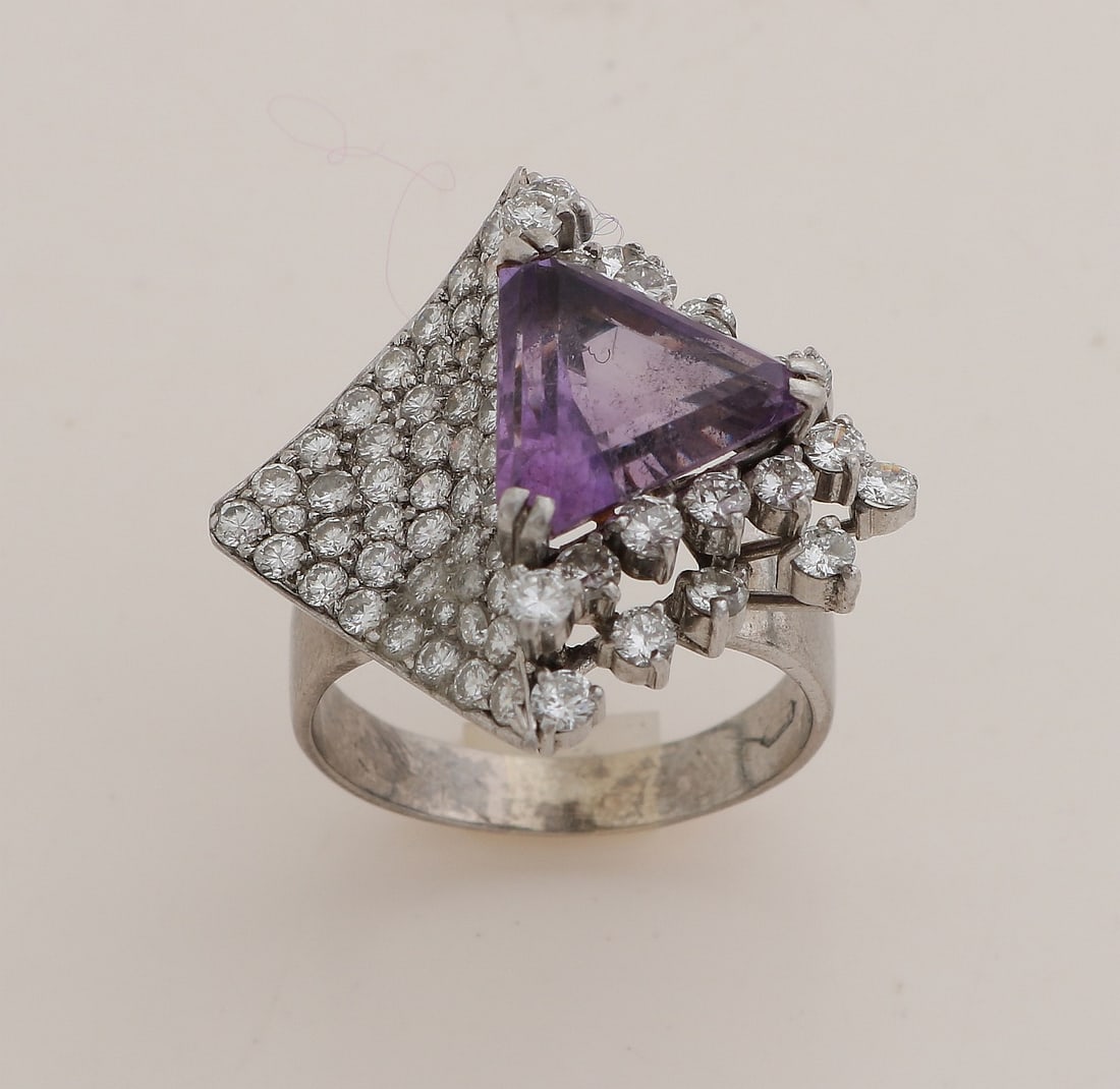 White gold ring with amethyst and diamond: White gold ring, 585/000, with amethyst and diamond. Ring with a rhombus-shaped head set with a triangle-cut amethyst, 12x12x12mm. Half of the rhombus is pavé-set with brilliant-cut diamonds, the hal