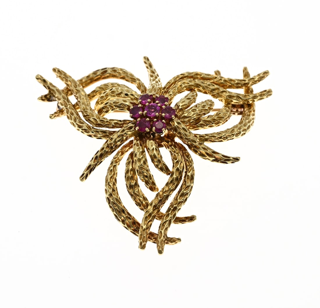 Gold brooch with ruby: Major yellow gold brooch, 750/000, with rubies. Brooch with floral swirl design in a triangular shape. Decorated in the center with a rosette set with 7 round faceted rubies. Stamped Tiffany. Approx.
