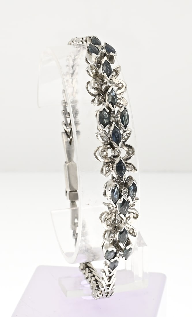 Silver bracelet: Silver bracelet, 925/000, with a hinged element featuring floral shapes, cubic zirconia, and blue/greenish faceted stones. Attached to a bracelet with V-shaped links. Length 19 cm. Width 10.5 mm.
