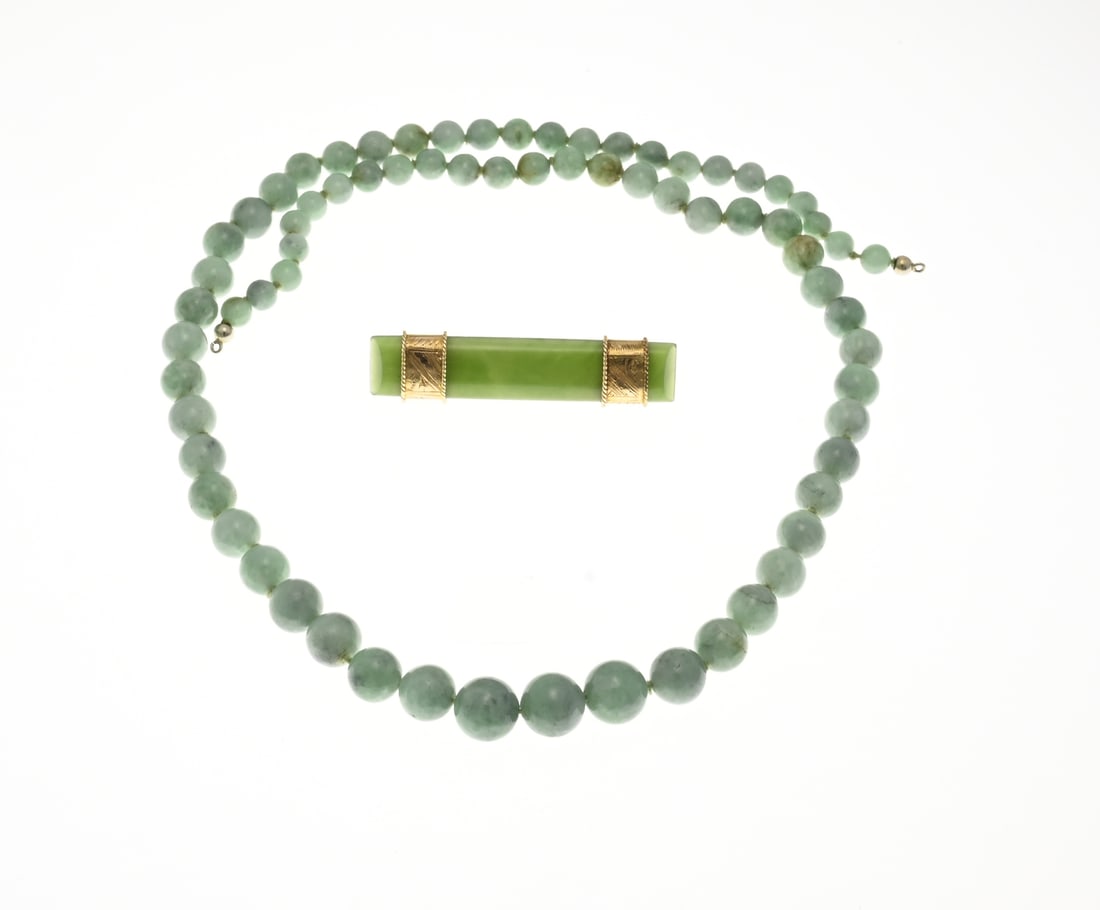 Bar brooch with jade and necklace: Jade brooch and necklace. Necklace with jade beads, tapering in size ø 5.5-9.5mm. 50 cm, without clasp. And a brooch made from a rectangular piece of jade by means of 2 yellow gold bands, 750/000,