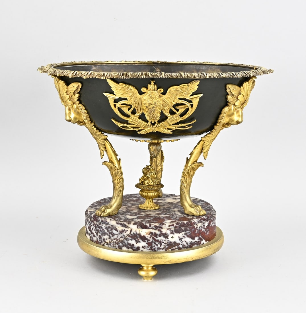 Grand bronze bowl Ø 37 cm.: Grand 19th-century French bowl, with gilded bronze lion heads, falcons, trumpets, and quivers, mounted on a marble base. Dimensions: H 32 x Ø 37 cm. In good condition.