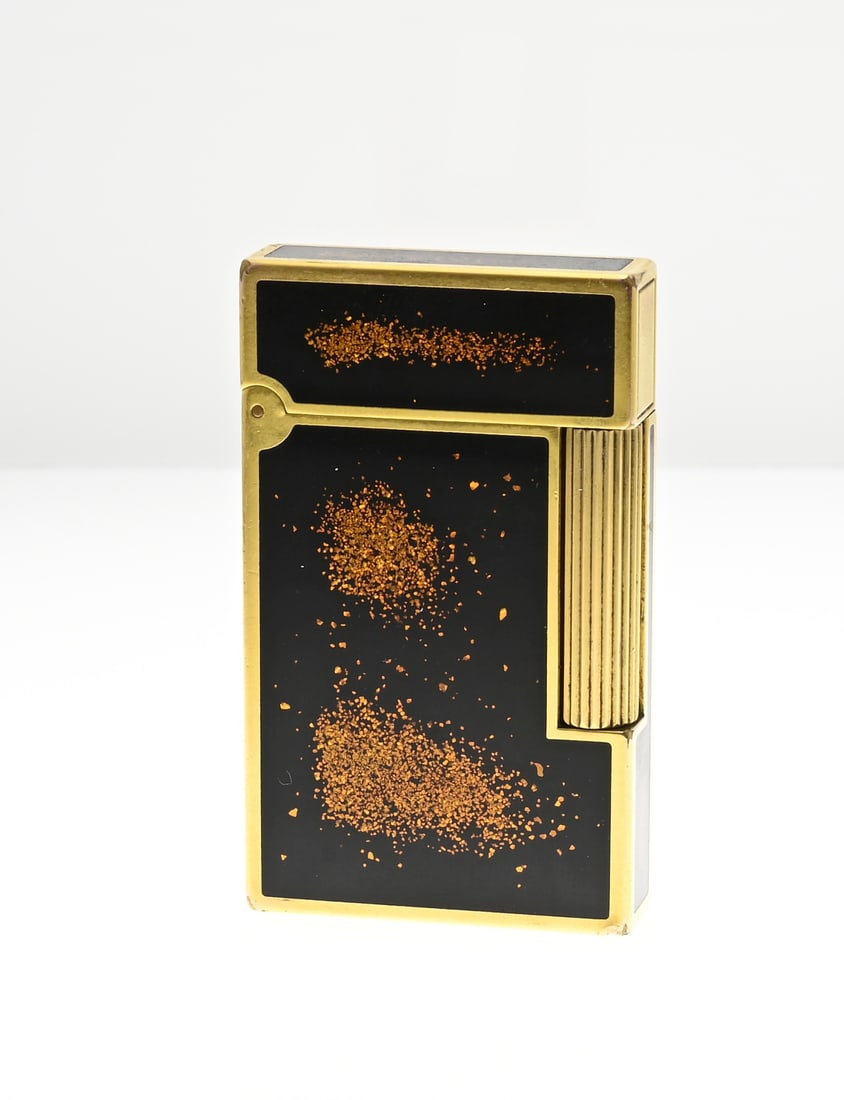 St. Dupont lighter: St. Dupont Ligne 2 Gold Dust lighter, gold-plated brass with black Chinese lacquer with gold dust particles. 12FKN19. 3.5x6x1cm. Some signs of use. In good condition.
