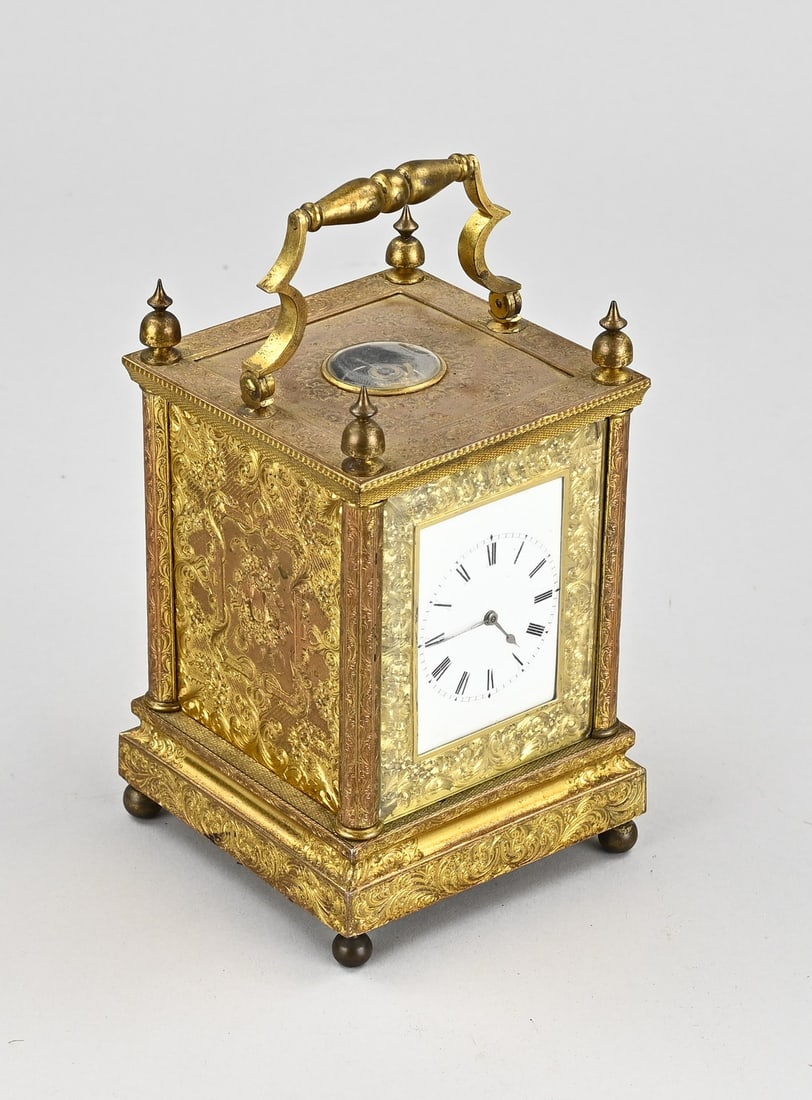 Antique travel alarm clock (France): Antique gilded brass travel alarm clock (Rofs, Exeter) with patent engraving, also engravings of angels + floral decoration. Eight-day movement. Dimensions: 15 x 8.5 x 10 cm. In good condition.