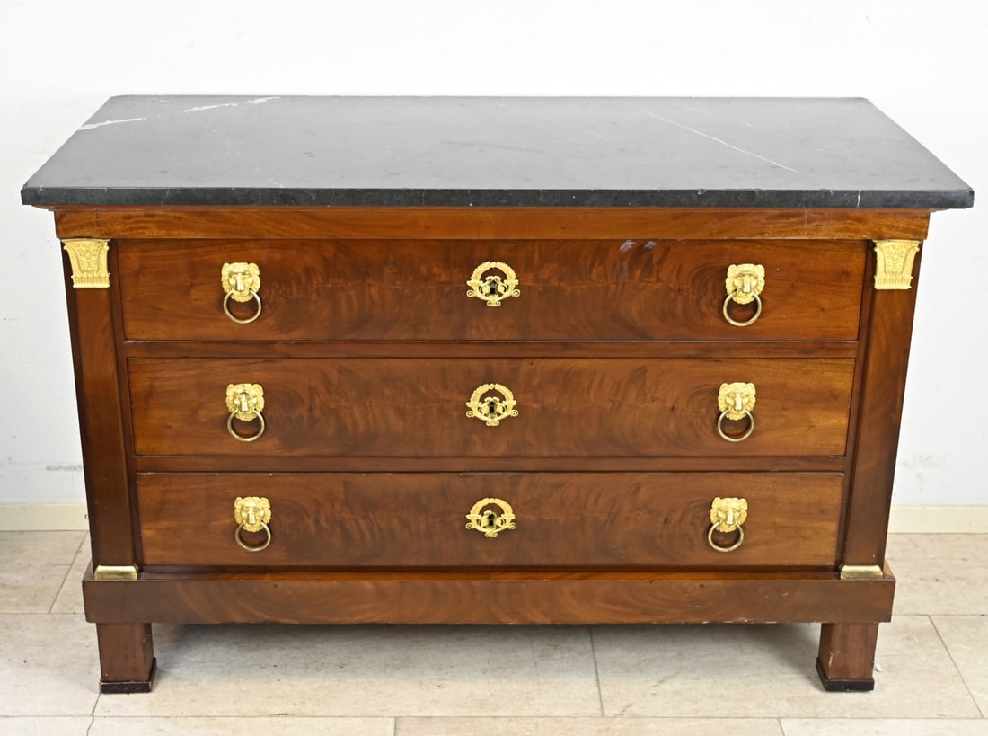 Empire chest of drawers: Early 19th-century Cuban mahogany Empire commode with original gilded brass fittings and black marble top. Dimensions: 86 x 132 x 60 cm. In good original condition.