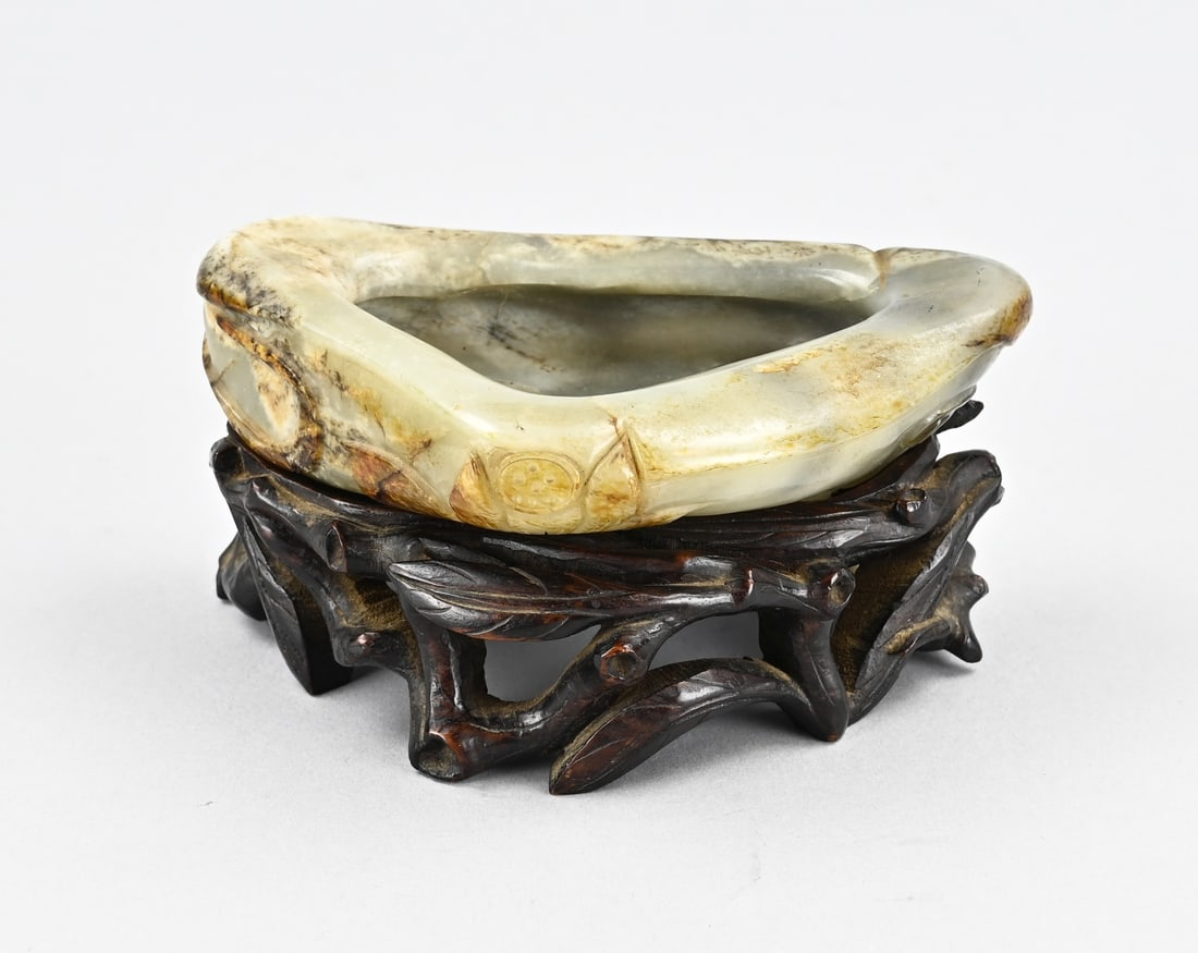 Jade bowl on wooden base: Old Chinese carved jade bowl with water lily decoration, placed on a console. Dimensions: 7 x 14 x 9 cm. In good condition.