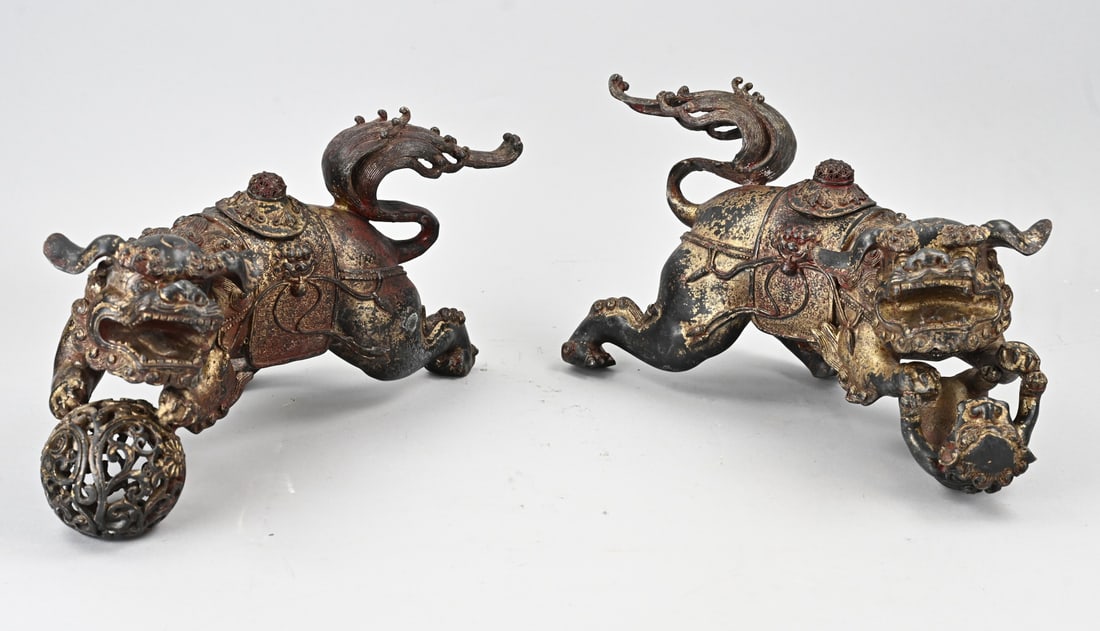 Set of bronze kylins: Two old/antique Chinese bronze kylins with play ball + lids on the back, with remaining gilding. Dimensions: 21 x 35 x 14 cm. In good condition.