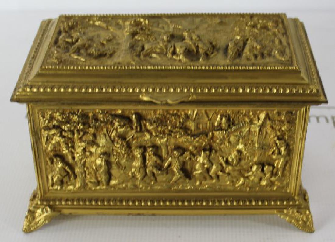 French Gilt Metal Jewelry Box: Antique 19th/20th French gilt jewelry box depicting various figures in an outdoor setting eating, drinking, cooking and dancing. Dimensions: 5 x 7 inches.