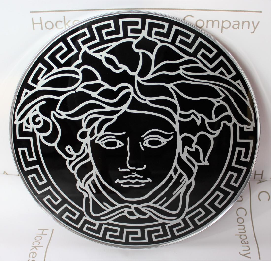 Versace Display: Versace black plexiglass Medusa head display sign. Dimensions: 15 x 1 inches.