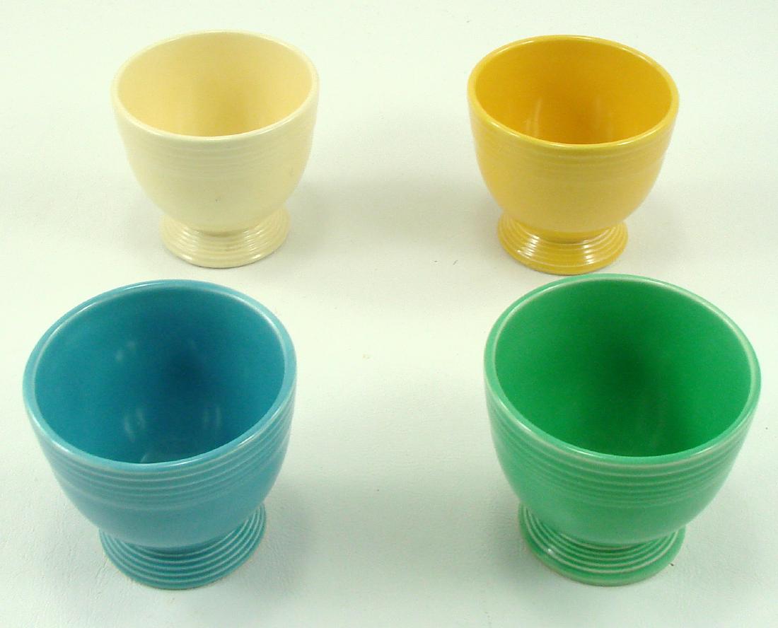(4) VINTAGE FIESTA EGG CUPS: In ivory, yellow, green, and turquoise; (3) stamped with impressed "HLC (monogram) Fiesta Made in USA"; green cup not marked; some "metal" marks to exterior of ivory cup; Dia.-3 3/8", H-3 1/8",VG- EX