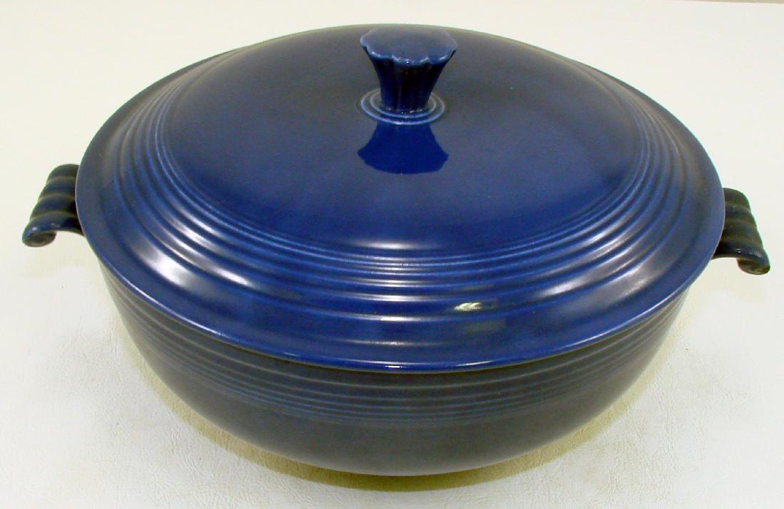 VINTAGE FIESTA COVERED CASSEROLE - COBALT: Two handled covered casserole with a foot; abrasion to edge of one handle; some roughness to edge of finial; impressed mark "Fiesta HLC USA"; L-9 3/4", H-5 3/4", VG