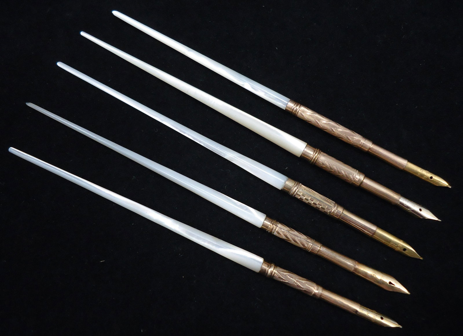 (5) MOTHER OF PEARL ANTIQUE DIP PENS: All with smooth mother of pearl tapered ends, unmarked gold colored metal grips; various engraved designs to grips - chevron, checkerboard, etc., Nibs: #3 with Wingflow nib, Parker fountain pen nib, A