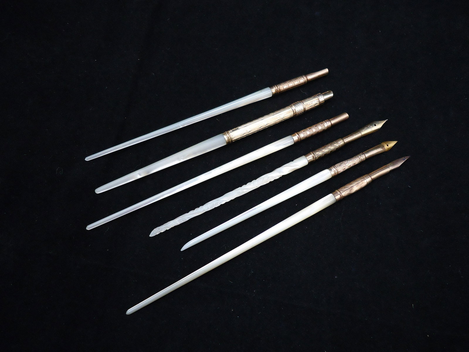 (6) MOTHER OF PEARL DIP PENS: (1) slid pen, no nib; (2) dip pens, no nibs; (1) A. Norton nib, grip dented; (1) Astro CU2 nib, carved handle, mother of pearl chipped on end; (1) Eternium nib, nib holder dented; L-6", G