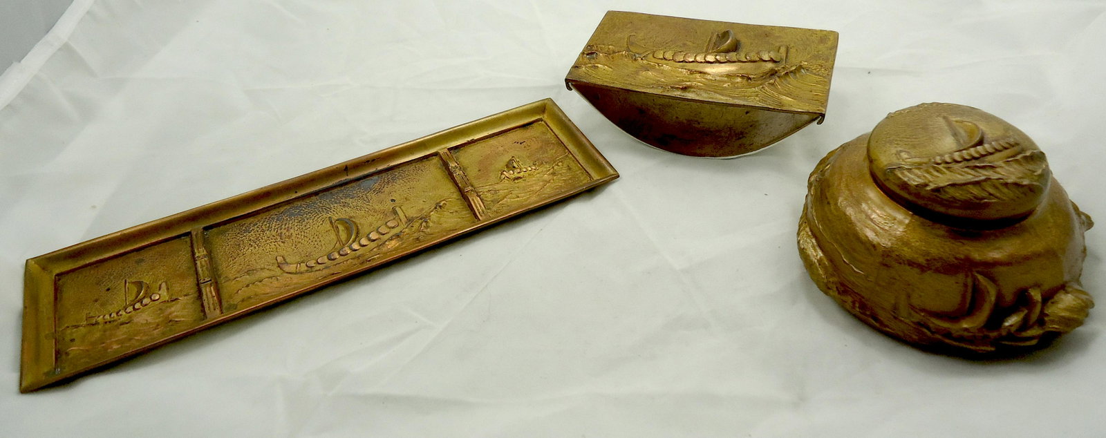 JENNINGS BROS. ARTS & CRAFTS VIKING SHIP DESK PIECES: Arts and Crafts era, bronze finish, each with a Viking ship in high relief; includes inkwell #2187, pen tray #2191, and rocking blotter #2188; some light wear to finish on pen tray; inkwell retains li