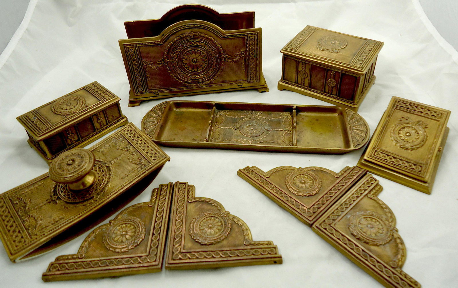 JENNINGS BROS. BRONZE (10) PIECE DESK SET: Very complete set with wreath and floral design; includes: paper clip #1864, (4) blotter corners #1863, inkwell, stamp box, rocking blotter #1860, pen tray #1850, and letter holder; some minor age dar