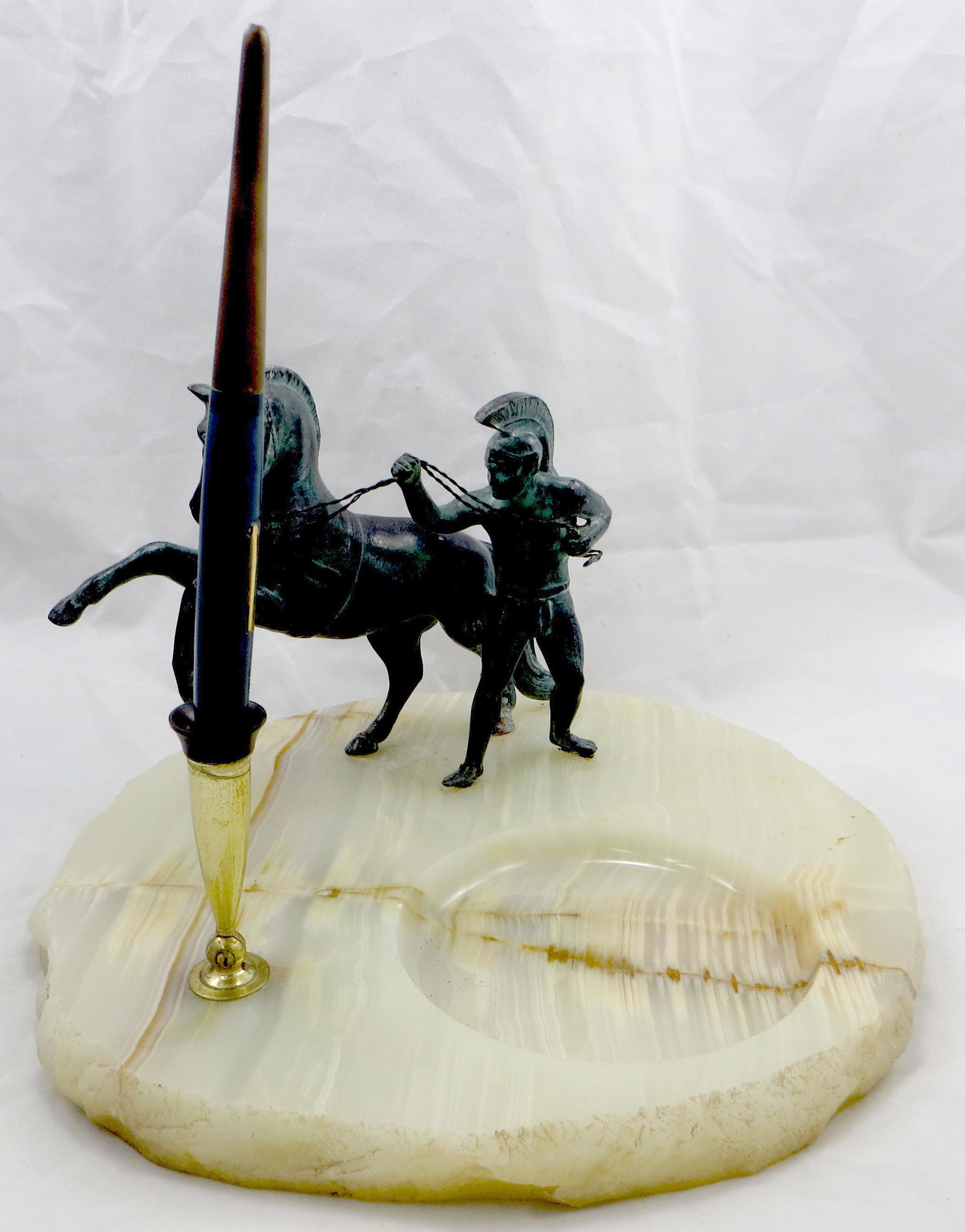 ROMAN GLADIATOR PEN HOLDER: Patinated metal figure of Roman Gladiator and rearing horse on onyx base; base has polished top and rough hewn edge; features round well for paper clips, etc.; underside together with Carter's blue de
