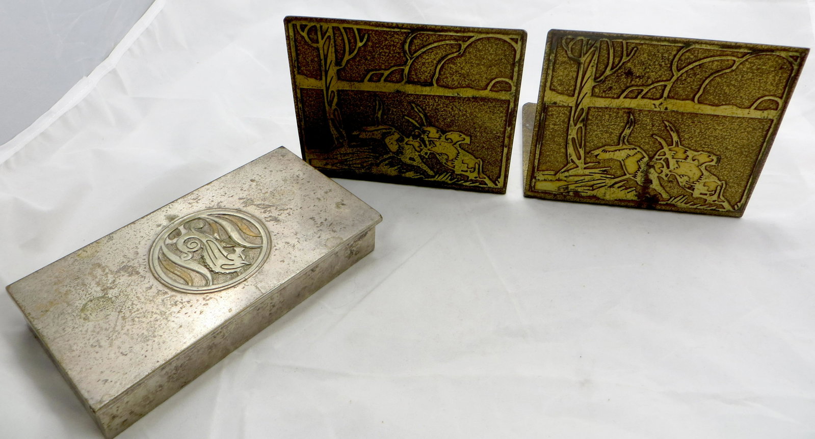 SILVERCREST BOOKENDS AND CIGARETTE BOX: Bronze; (1) Pair Bookends: relief scene of dogs running; some scratches and discoloration; (1) cigarette box: seahorse motif, silver over bronze; wood lined interior, missing divider, metal spotty; lo