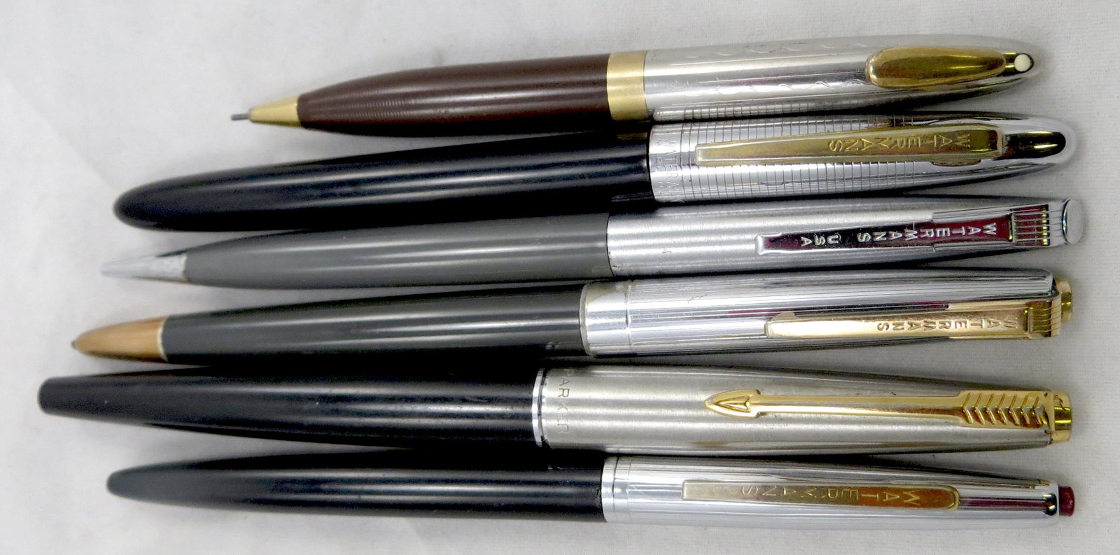 (6) WATERMAN, SHEAFFER & PARKER PENS/PENCILS: (1) Parker felt tip (dried); (1) Sheaffer pencil, chrome & brown; (4) Waterman: (2) pencils with gray barrels, erasers hardened, 1-worn; (2) ball point pens, black barrels, spring mechanism not workin