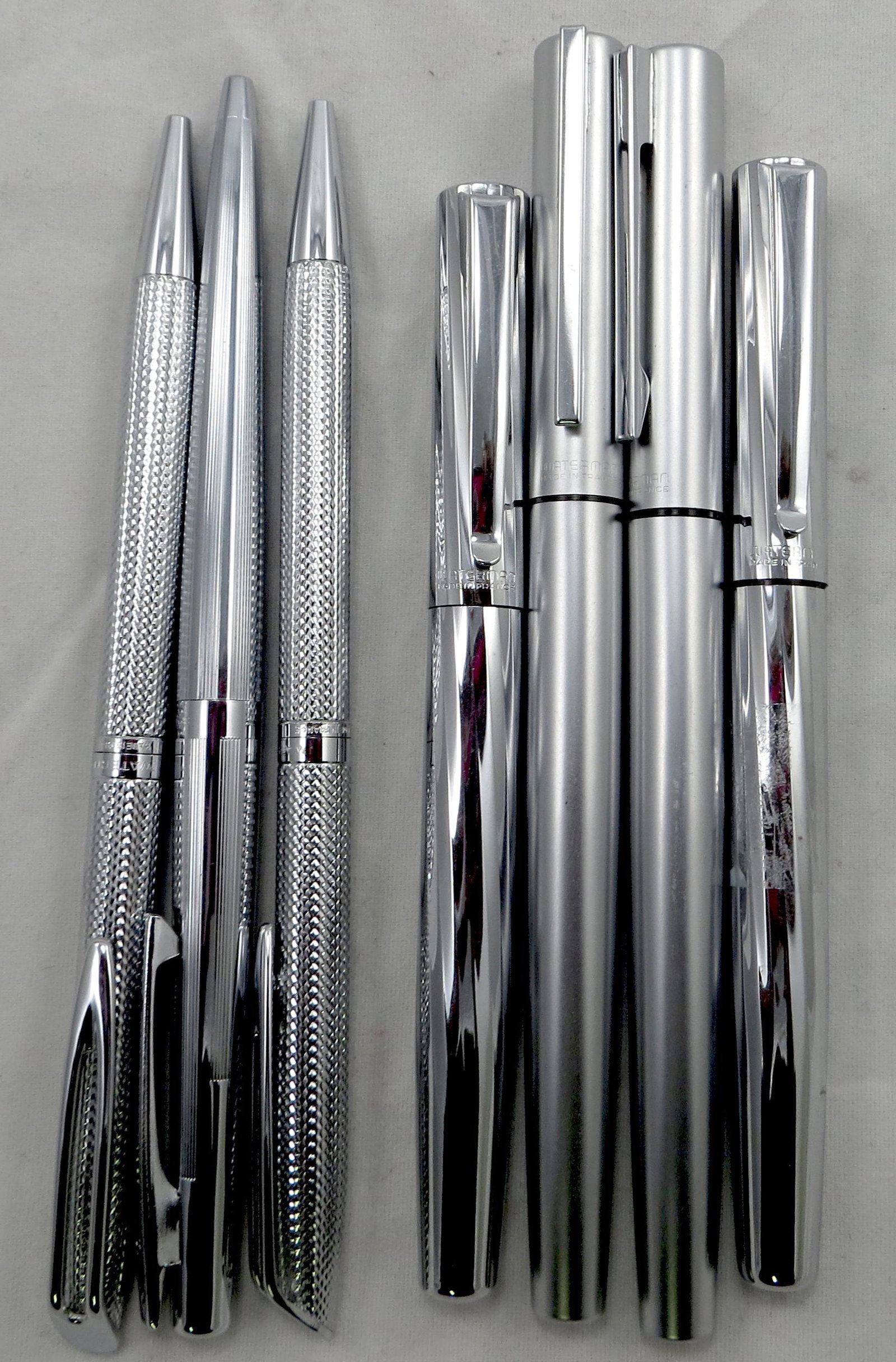 (7) WATERMAN & SHEAFFER PENS: Chrome and Silvertone, French, etc.; (2) 1980's fountain pens with medium ibs; (2) brushed silvertone fountain pens, (1) has loose nib; (2) chrome ballpoints; (1) Sheaffer ball point; all needing new 