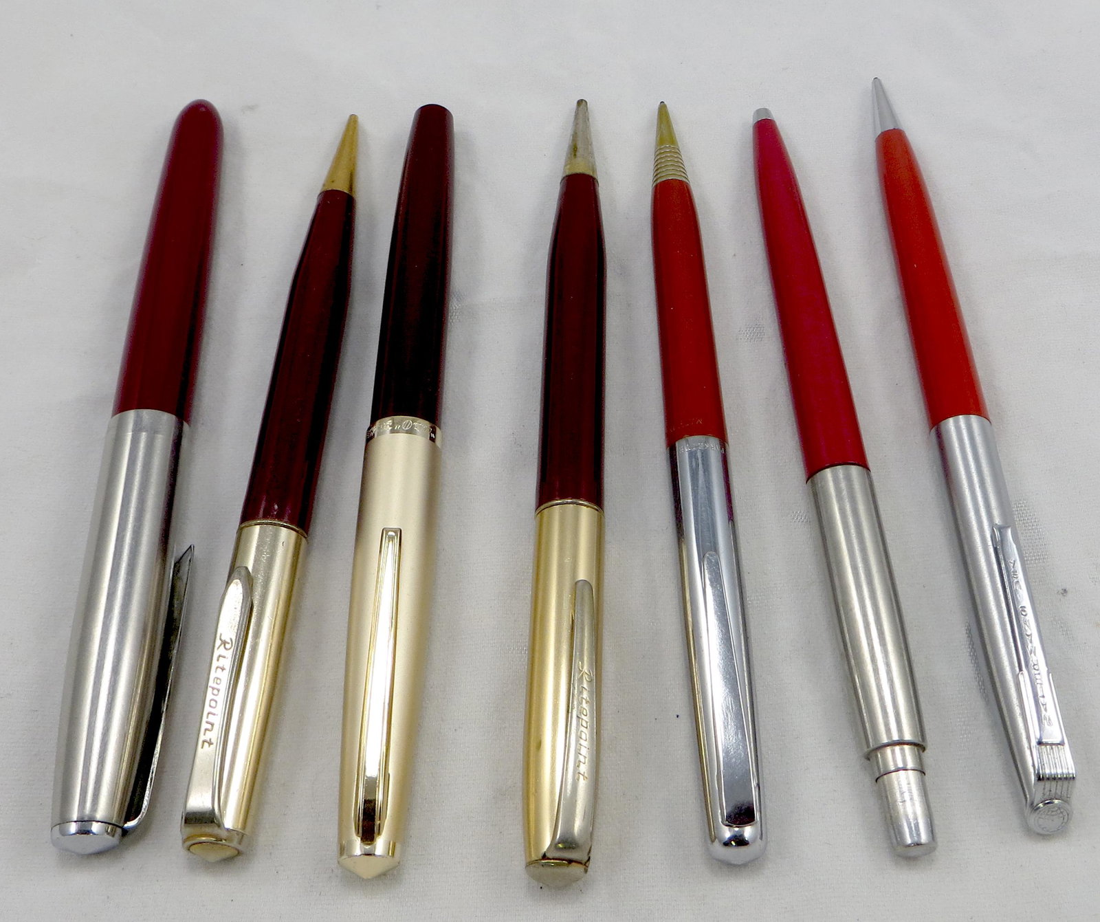 (7) VINTAGE PENS & PENCILS: Burgundy and red bodies: (2) Ritepoint pencils, (1) Waterman pencil; (1) Parkette twist pencil; (1) Parker "21" fountain pen; (1) Hero fountain pen; (1) Parker ballpoint, no clip; longest L-5 1/2", G-