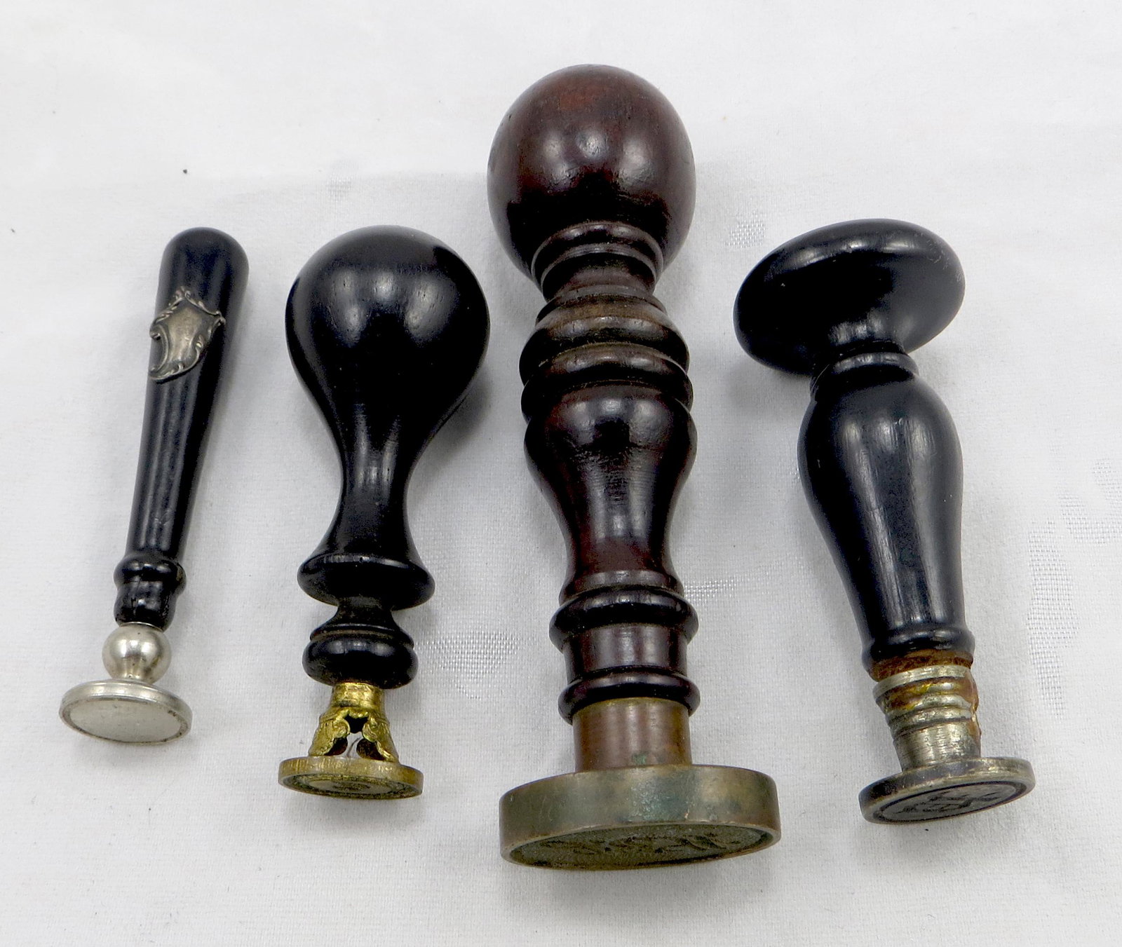 (4) WOOD HAFT DESK SEALS: Includes: (1) urn shaped ebonized wood haft, fleur de lis stand, brass "D" seal; (1) bat form ebonized haft with silver plaque (not engraved), no seal; (1) turned wood haft with "mushroom" knob, brass