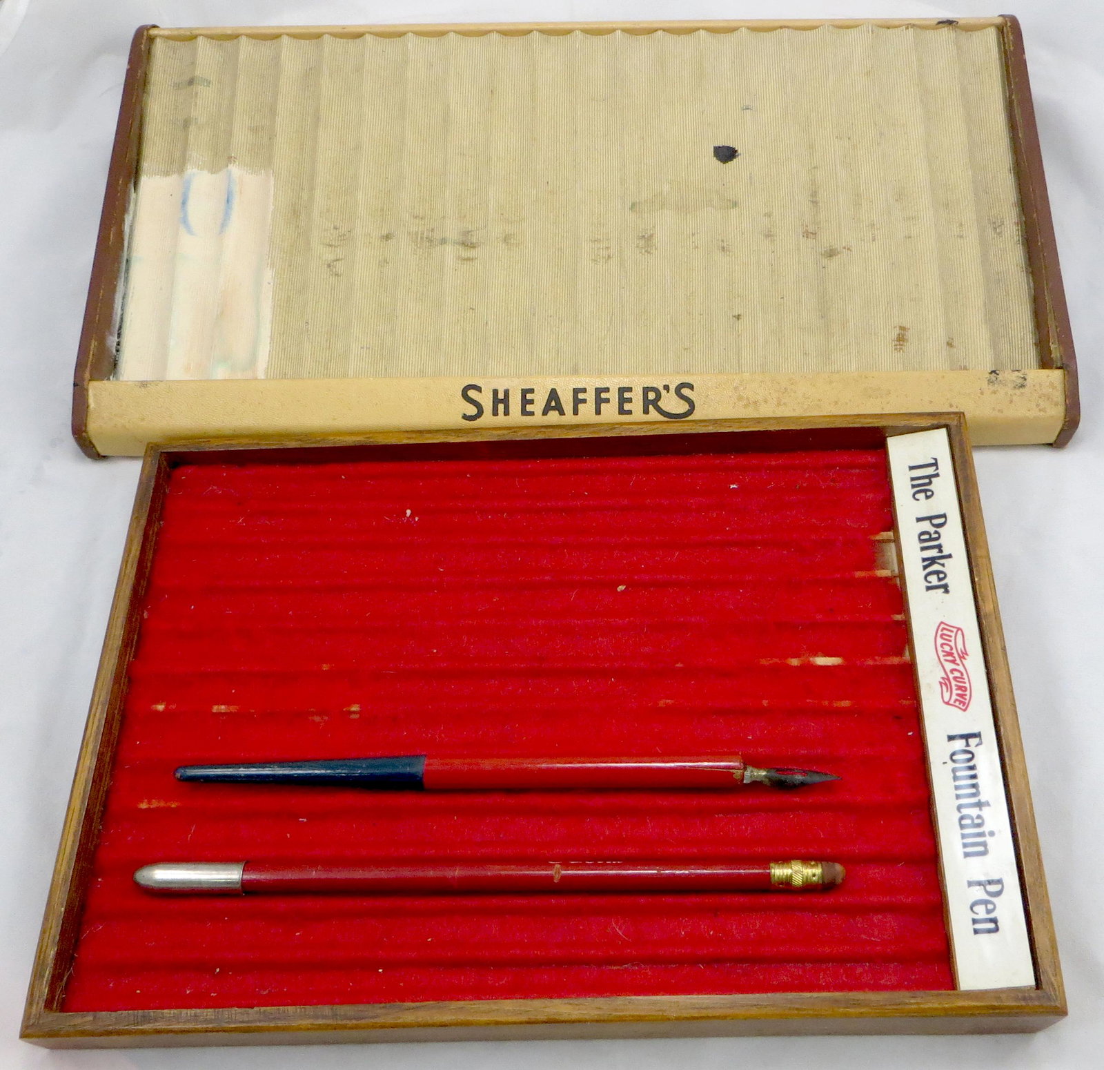 (4) VINTAGE ADVERTISING PENS, PENCILS, DISPLAYS: (1) Coca-Cola pencil - dents, dry eraser; (1) Coca-Cola dip pen - small wood splits, lettering worn; (1) 1950's Sheaffer Pen display, (20) slots, overall staining; (1) Parker Fountain Pen Lucky Curve 
