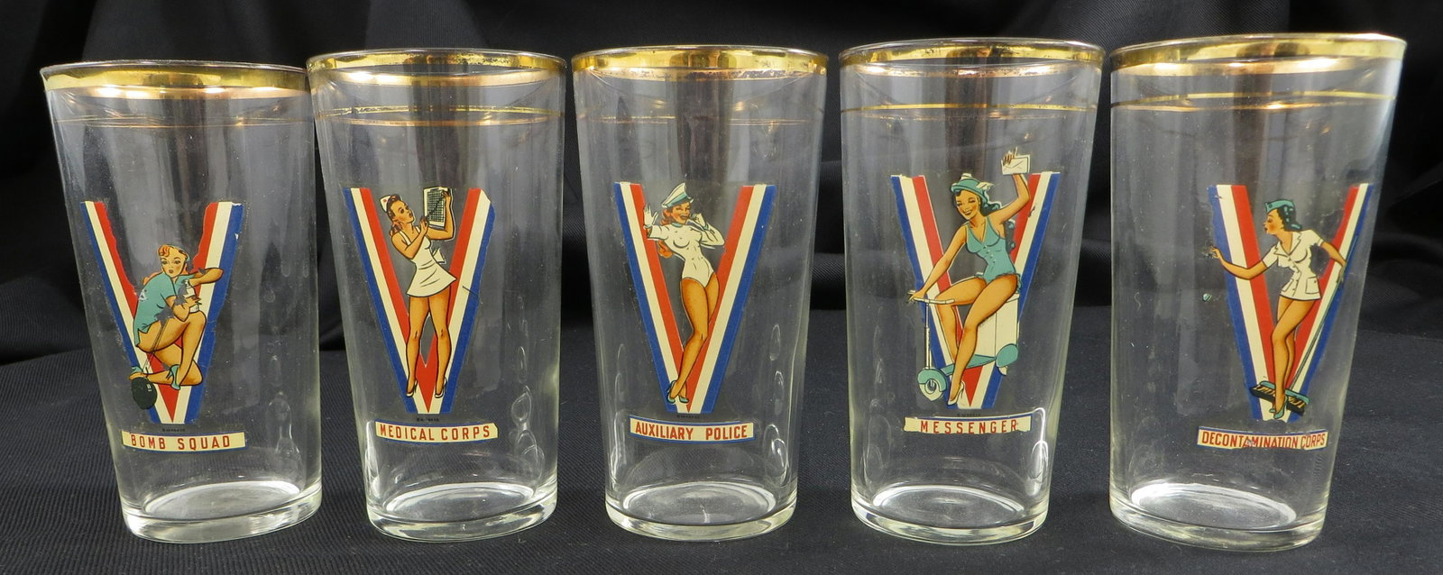 (5) 1942 WWII PIN-UP GIRL GLASSES: Medical Corps, Decontamination Corps, Messenger, Bomb Squad and Auxiliary Police; gold bands have rubbing; pictorial decals have minor losses; H-5", G-VG