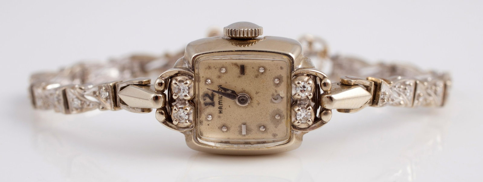 HAMILTON WHITE GOLD & DIAMOND WATCH: 14K white gold; (22) .01+/- carat diamonds on band, bezel set with (4) .03 +/- carat diamonds; has safety chain; watch untested; normal wear; 15.97 grams total; watch face 1/2", G-VG