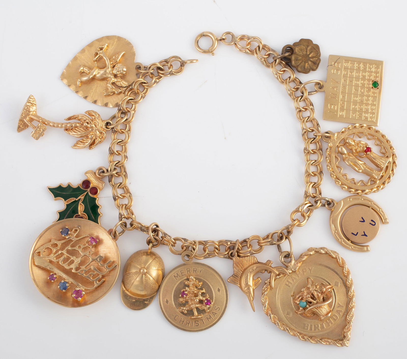 14K YELLOW GOLD CHARM BRACELET: charms include: cherub on heart, jockey hat, "Happy Birthday" with gemstones, "Merry Christmas" circle with gemstones, shark, "Happy Birthday" with stones missing; "I Love You" spinner; husband and wi