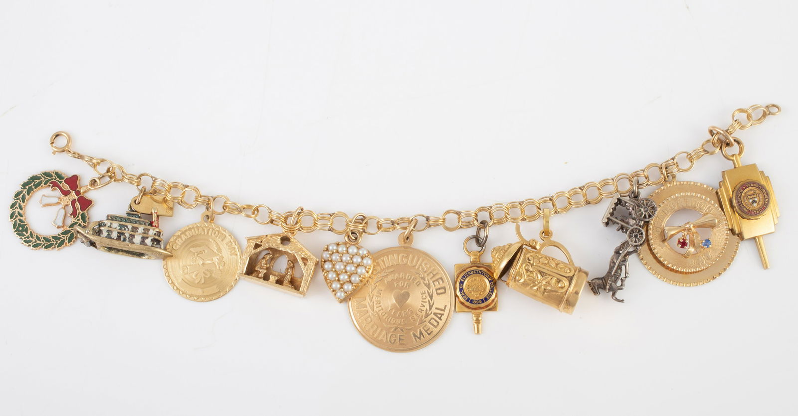 14K YELLOW GOLD CHARM BRACELET: charms include: PA University (gold filled); graduation charm with stones; sterling "Nassau" horse pulling cart; 18K tankard with hinged lid; unmarked seal of Elizabethtown; 14K marriage medal; 14K pe