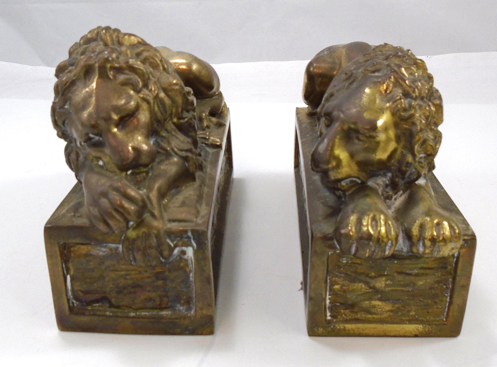 PATINATED METAL LION BOOKENDS: Reclining lions on rectangular bases; gilt / brass patination; filled for weight; lions mimic the famous Canova marble lions; felt bottoms; some overall wear and oxidation; H-4 1/2", L-7 3/4", G-VG