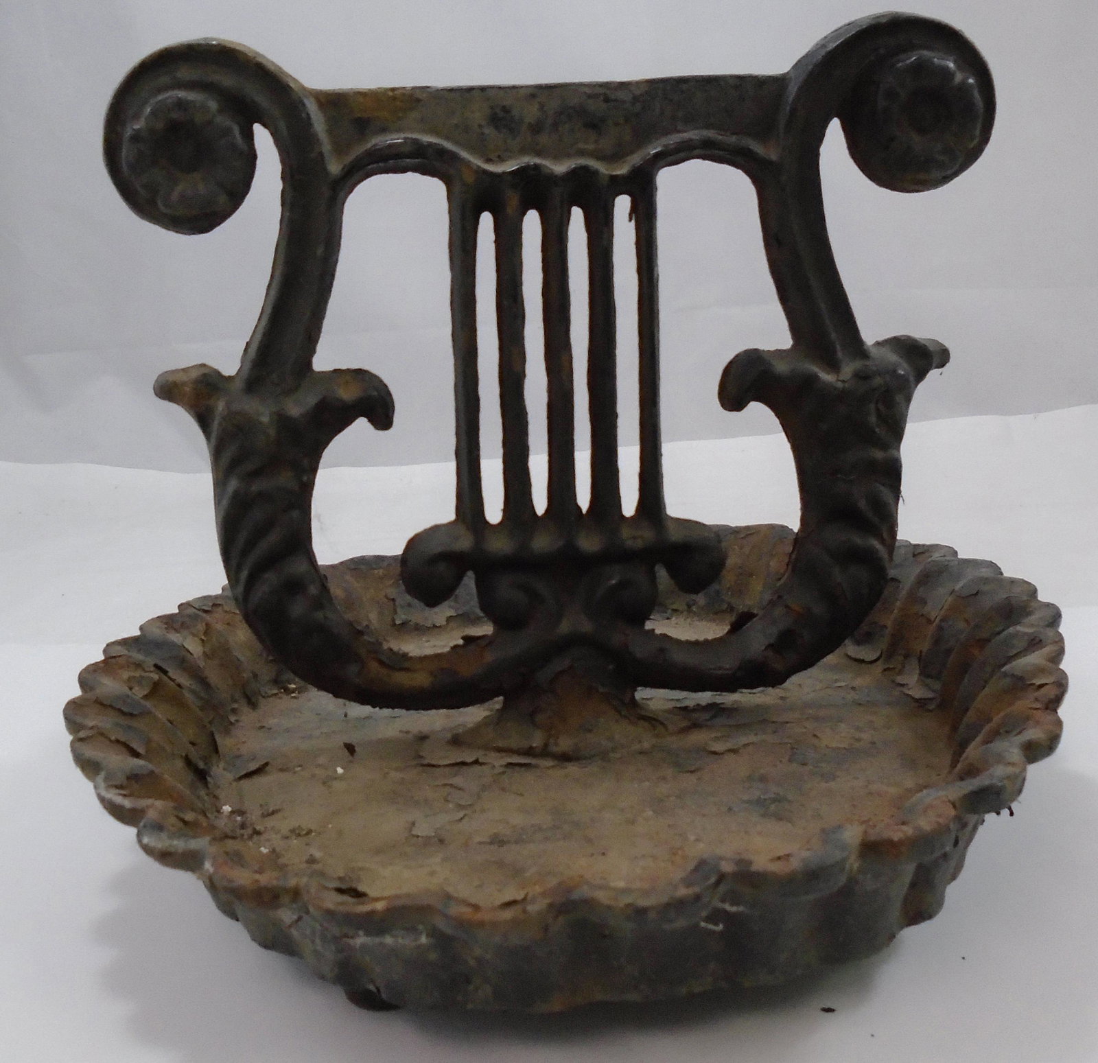 CAST IRON LYRE FORM BOOT SCRAPE: Painted cast iron; lyre form scrape in scalloped cast iron tray; paint flaking extensively; marked on underside VTMG; rusty; H-7 3/4", L-11", G