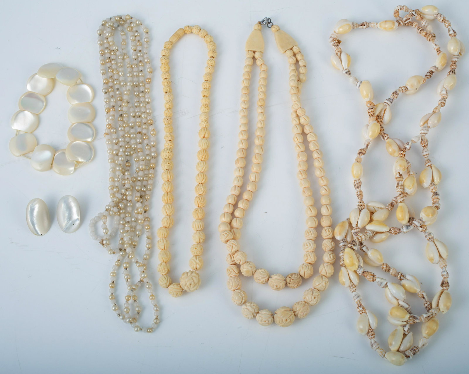 (6) PCS. BONE, SHELL, MOTHER OF PEARL, ETC. JEWELRY: Includes: (1) single strand carved bone necklace; (1) double strand carved bone necklace; (1) mother of pearl bead bracelet (elastic is weak); (1) pair clip-on mother of pearl earrings; (1) cowrie she