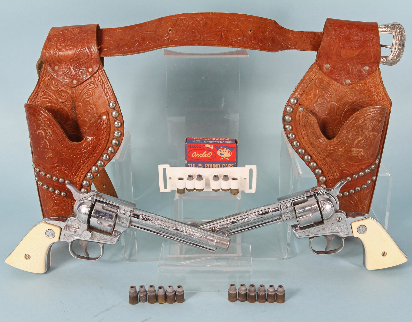 PAIR OF NICHOLS STALLIONS .38 CAP GUN with HOLSTER: (2) cap guns, each with (6) bullets; leather holster set with belt, (6) additional bullets on plastic strap and box of Circle O round caps; guns L-10 1/4";