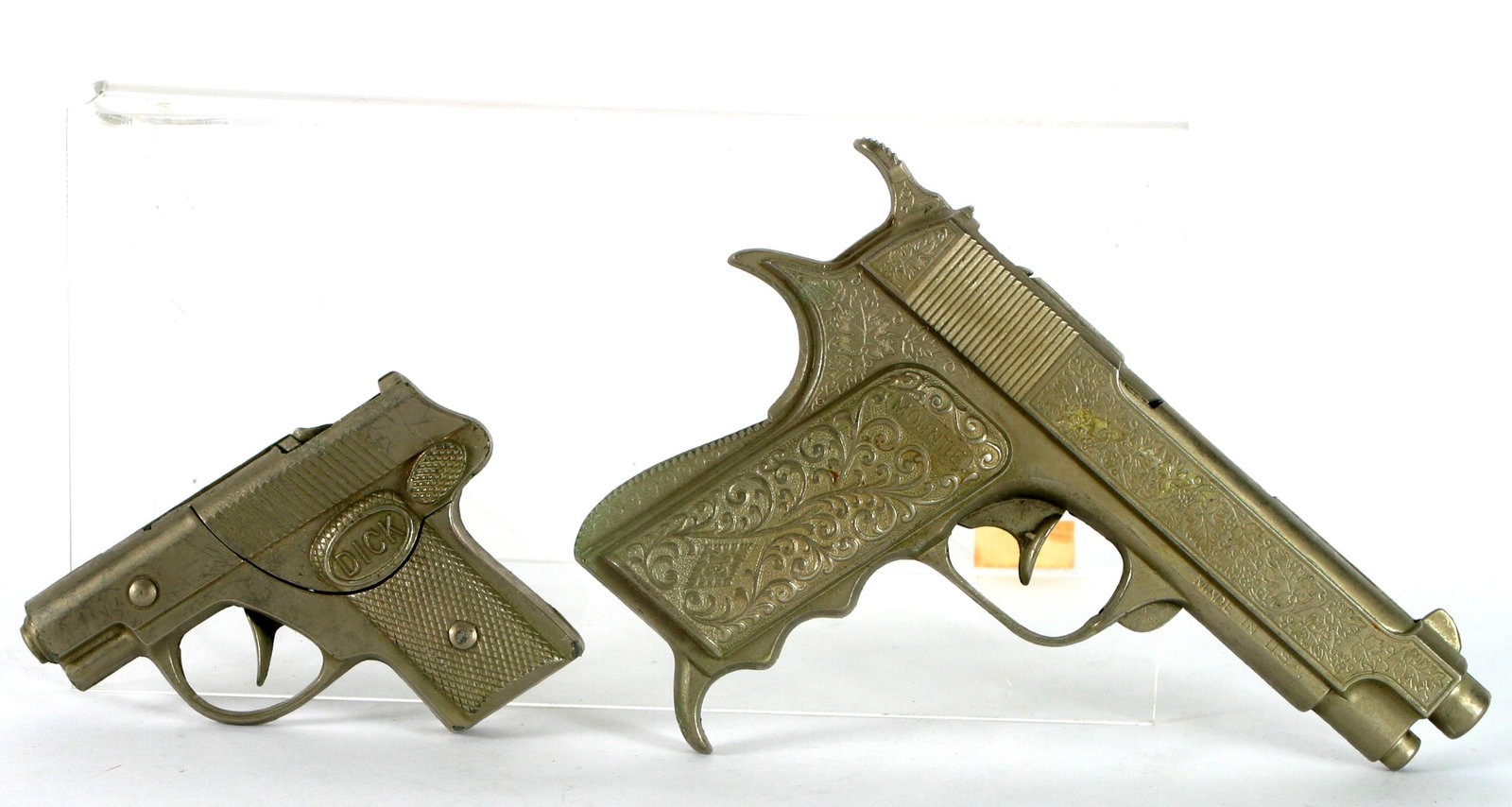 (2) VINTAGE HUBLEY CAP GUNS: MOUNTIE & DICK: (1) Hubley Mountie .45 cap gun; silvertone grape and vine embossed metal; made in USA; 7" X 4 1/2"; (1) Hubley Dick repeater takes coil caps, all-metal; L-4";