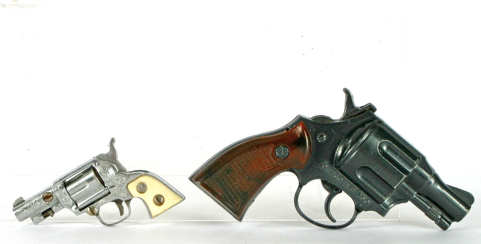 (2) VINTAGE NICHOLS CAP GUNS: PINTO & DETECTIVE: (1) Nichols mini Pinto cap gun; single action; white grips; possibly 1960's; silvertone metal; retains orginal bullet in cylinder; L-3 1/2"; (1) Nichols Detective 250 pistol cap gun; L-5";